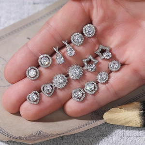 Macro shot of silver stud earring set with flower and star shapes in hand