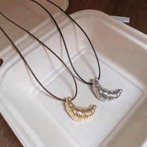 Minimalist croissant pendant necklace with leather cord in a creative food box display