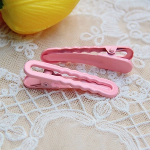 Two pink macaron hair clips on lace fabric with elegant floral background
