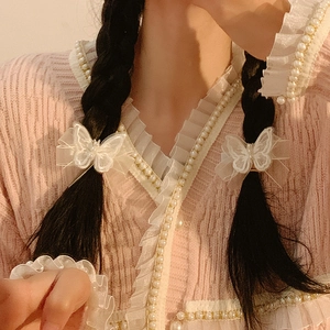 Elegant white mesh bow hair clip with pearl center on model with pink knit cardigan