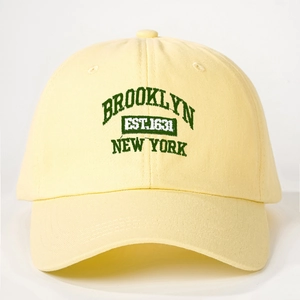 Detailed close-up of dark green Brooklyn embroidery on yellow cotton baseball cap