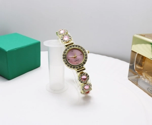 Detail of luxury gold watch with pink dial and floral rhinestone bracelet on display stand