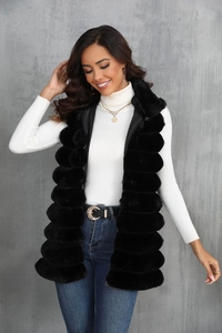 Détail de la texture d'un gilet en fausse fourrure noire sur un col roulé blanc