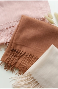 Dettaglio di sciarpe in lino e cotone rosa e beige con eleganti nappe sui bordi