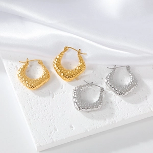Gros plan de boucles d'oreilles en U dorées et argentées avec texture martelée sur soie