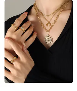Close-up of layered 18K gold plated necklaces featuring moon and lion head pendants
