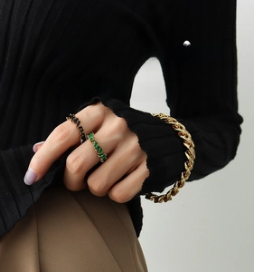 Detailed view of 18K gold plated curb chain and rings with green and black zircon stones