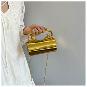 Detailed shot of golden cylindrical evening bag with lion head relief and chain strap