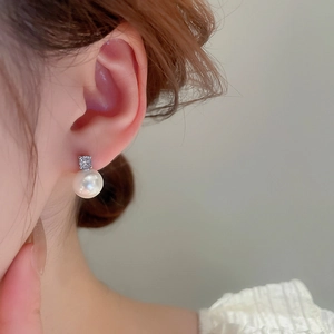 Close-up of minimalist pearl stud earring with cubic zirconia on model's ear