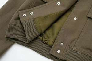 Detailed macro view of military green cotton canvas jacket with silver metal snap buttons