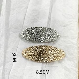 Macro view of gold and silver alloy hair clips with unique hammered texture and dimensions