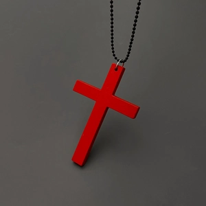 Detail of a matte red cross pendant hanging on a black ball chain necklace
