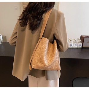 Detailed view of khaki shoulder bag with faux crocodile texture on a stylish model