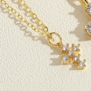 Macro view of a 14K gold-plated cross pendant featuring six sparkling cubic zirconia stones