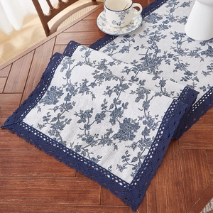 Detailed close-up of blue floral table runner with intricate navy lace crochet borders
