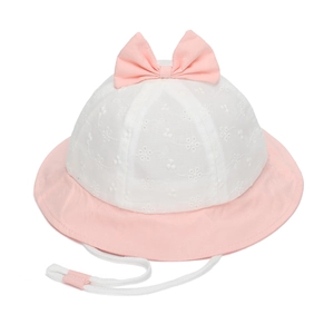 Détail de broderie de fleurs blanches et nœud rose sur un chapeau de soleil pour bébé