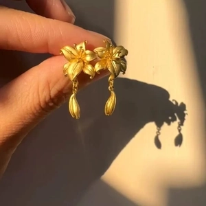 Detailed view of matte gold lily flower earrings with elegant hanging bud tassels