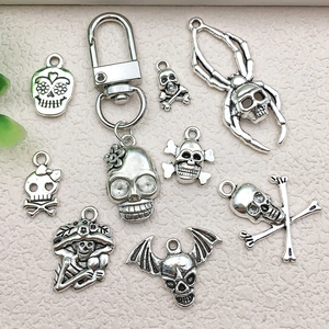 Vintage silver skull alloy charms for DIY Halloween earrings and keychains on textured fabric