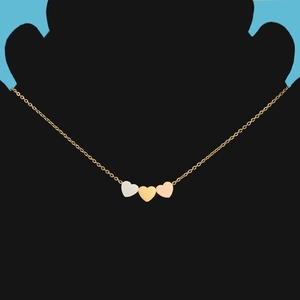 Detailed view of triple heart pendants in gold, silver and rose gold on a thin chain