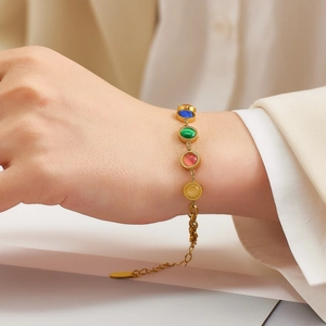 Macro shot of gold stainless steel chain bracelet with colorful cat-eye stones on wrist