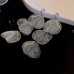 Detail of silver fish-tail tassel earrings with zircon studs on black glossy surface