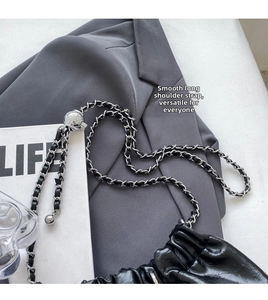 Detail of black glossy pleated bag featuring metal chain strap and spherical slider