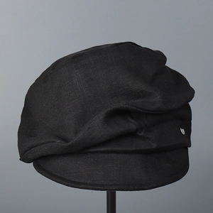 Detail of black newsboy hat featuring textured cotton linen fabric and metal buckle