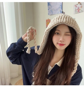 Détail du bonnet en grosse maille abricot avec protège-oreilles et tresses