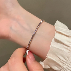 Gros plan d'un bracelet tennis en cristal violet avec finition or rose et fermoir coulissant