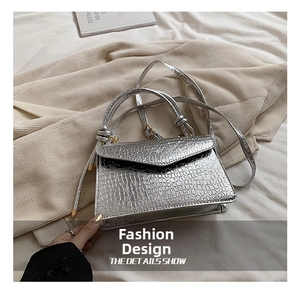 Detail shot of silver faux crocodile leather texture and V-shaped flap closure on handbag