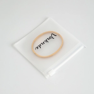 Detail of a minimalist gold bangle inside a frosted matte EVA zipper storage pouch