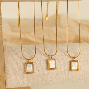 Collier en acier titane doré avec pendentif rectangulaire en nacre sur porte-bijoux