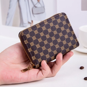 Brown leather coin purse with golden clover print and metal zipper closure