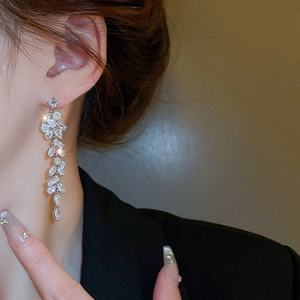 Close-up of elegant leaf-shaped tassel earrings with zircon inlay on a female model