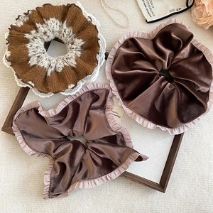 Detailed shot of brown lace and velvet scrunchies set on elegant wooden frame decor