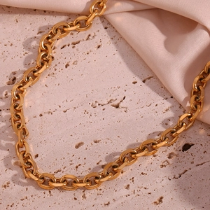Detailed view of 18K gold plated stainless steel chain on beige stone and silk background