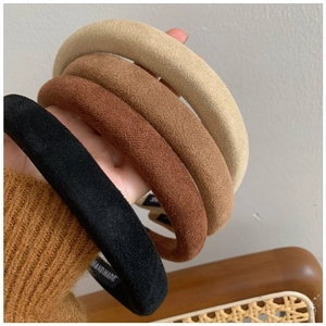 Detail of four thick suede headbands in black, brown, and beige with handmade label