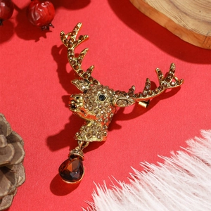 Detail of a vintage golden elk brooch with champagne rhinestones on a festive red background