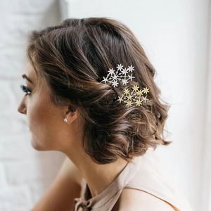 Star-shaped hair clips with rhinestones in gold and silver worn on side of short hair