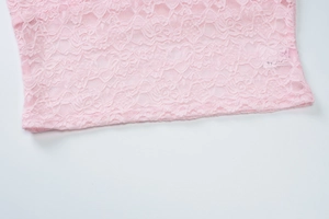 Close-up of pink lace fabric showing intricate floral crochet patterns on a white background