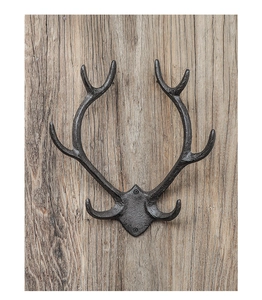 Detail view of rustic cast iron antler wall hook with matte black finish on wood