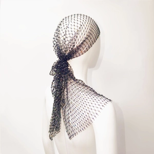 Dettaglio del foulard a rete nera con perline colorate su una testa di manichino