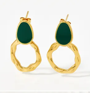 Detail of vintage gold plated earrings with dark green enamel and irregular wavy hoops
