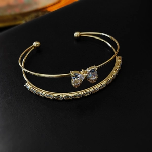Detailed view of golden double-layer bow bracelet with zircon and rhinestone inlay