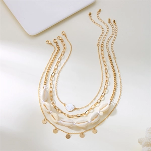 Summer gold layered necklace set with white shells, pearls and starfish charms on a white tray