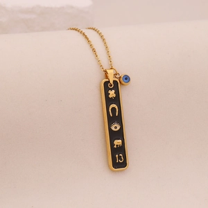 Détail d'un collier doré avec pendentif en émail noir et porte-bonheur sur tissu doux