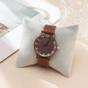 Detail view of a vintage brown women's watch with artistic numerals on a velvet pillow