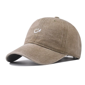 Detail of embroidered white smiley face on washed cotton khaki baseball cap texture