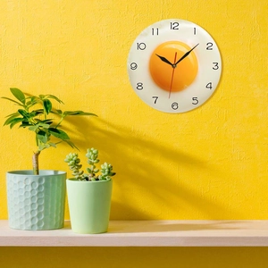 Close-up of the creative fried egg wall clock hanging on a vibrant yellow kitchen wall