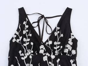 Vue détaillée de la broderie florale blanche sur une robe noire dos nu